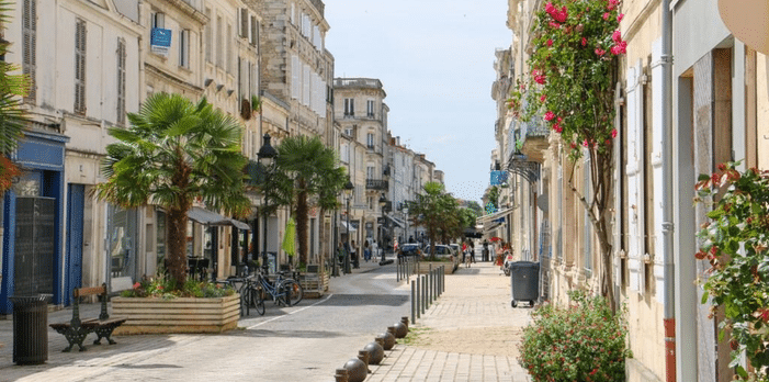 Rue du centre de Rochefort bordée de façades en pierre et de palmiers